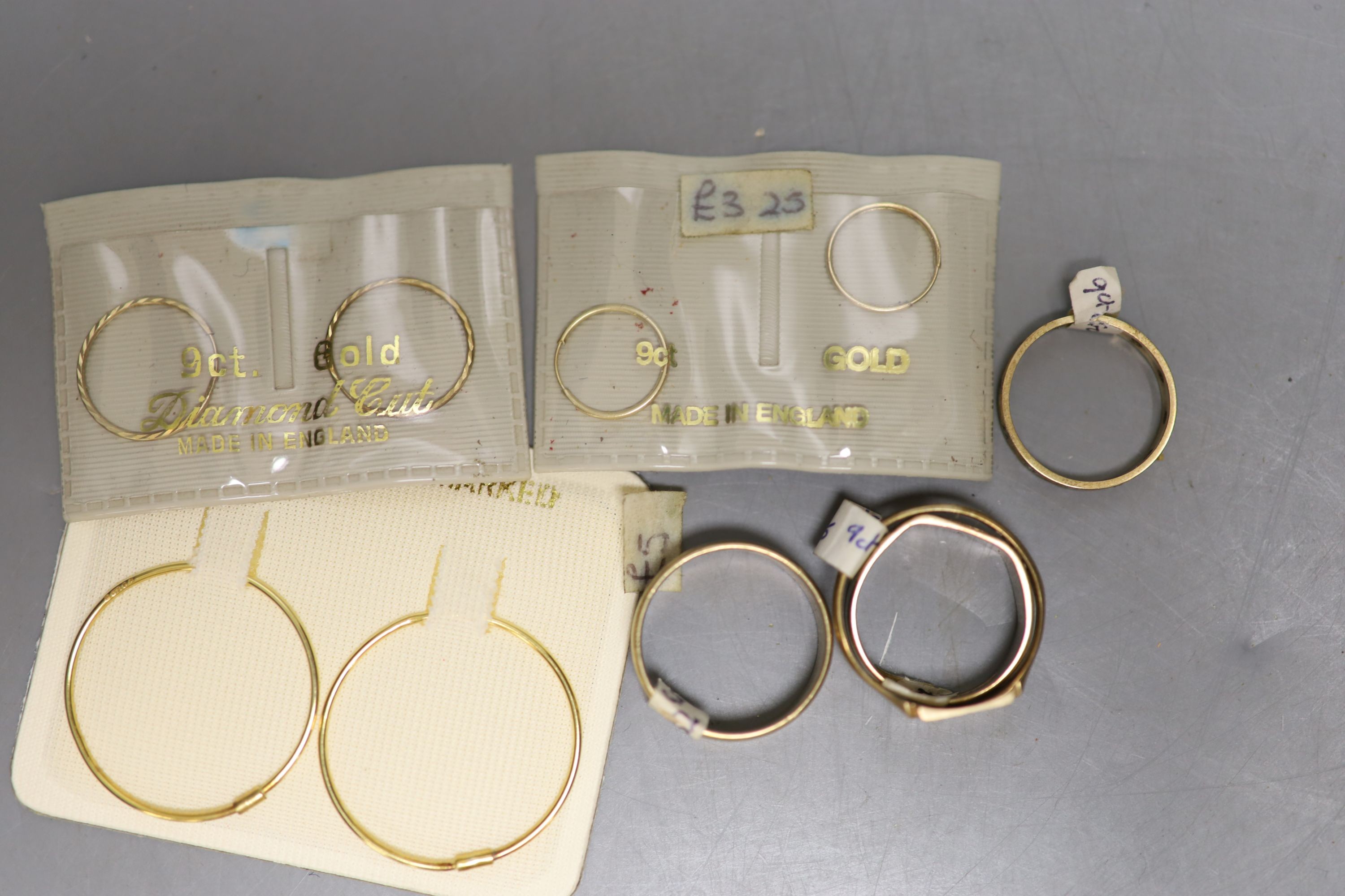 Four assorted 9ct rings, 13.5 grams and three pairs of 9ct hoop earrings in original packaging.